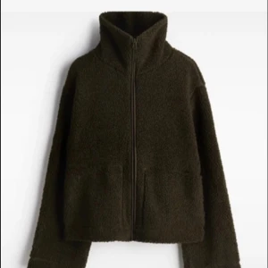 Mörkgrön teddyjacka med dragkedja - Trendig mörkgrön teddyjacka från H&M. Jackan har hög krage och hel dragkedja framtill, samt två stora fickor. Perfekt för kalla dagar när du vill vara både bekväm och snygg.