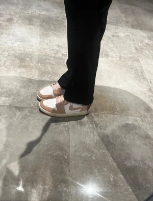 Nike Air Jordan 1 Mid SE rosa/vit - Nike Air Jordan 1 Mid SE sneakers i en snygg kombination av ljusrosa och vitt. KÖPTE DEM FÖR 2000 KR!!Skorna har högt skaft, snörning och en rund tå. Ovandelen är tillverkad i mocka och skinn, med klassisk Swoosh-logga på sidan. Perfekt för dig som gillar streetwear och vill sticka ut.