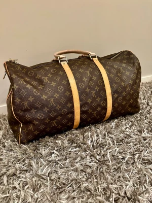 Louis Vuitton Keepall Bandoulière 50 i monogramcanvas.  - Säljer nu min extremt fina Louis Vuitton väska. Som är perfekt för dig som ska ut och resa eller bara vill se lyxigare ut i vardagen. Väskan har blivit lite solblekt och på handtagen axelremmen medkommer ej! Därför jag säljer billigt! Hör av dig vid intresse, mvh Melwin🙌