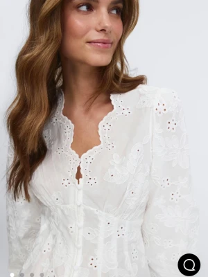 Vit broderad blus med knappar - Säljer denna trendiga Superfina vit blusen från gina tricot som är slutsåld, storlek xs helt ny med prislapp kvar. Blusen har broderade blommor och hålmönster. Blusen har långärmade puffärmar, knappar framtill och en söt vågig kant vid halsringningen. 