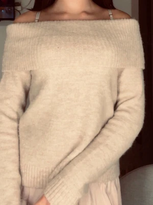 Beige off shoulder stickad tröja - Mysig beige stickad tröja med off shoulder-design och bred ribbad kant upptill. Tröjan har långa ärmar och ribbade muddar vid ärmslut och nederkant. Perfekt för en avslappnad men ändå trendig look. Från gina Young i strl 164 och inga skador/tecken på användning. Snabb affär pris kan sänkas!!