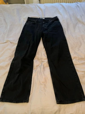 Svarta wide jeans från Junkyard - Säljer ett par svarta jeans från Junkyard i storlek 31. Modellen har en bred, relaxed passform med raka ben och klassisk femficksdesign. Perfekta för dig som gillar en loose och trendig stil. Materialet är tåligt denim i bomull.