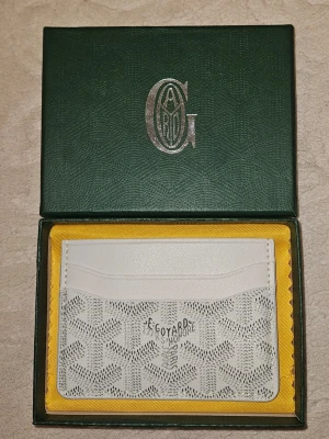 Vit Goy4rd plånbok  - Snygg vit plånbok, exklusivt skinn med det klassiska mönstret och flera kortfack. Kommer i original grön box med gul insida. Perfekt för dig som vill ha något stilrent och lyxigt i fickan.