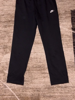 Svarta mjukisbyxor från Nike XL - Svarta mjukisbyxor från Nike i storlek XL. Byxorna har en enkel och clean design med Nike-logga på låret, elastisk midja och är gjorda i en mjuk bomullsblandning. Perfekta för chill eller träning.