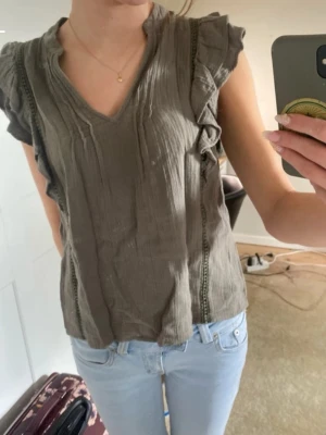 Grön volangblus med v-ringning  - Såå söt blus med volang och detaljer från Vila i storlek 34. Har  tyvärr inte kommit till användning. Perfekt till sommaren! Köpt för 500