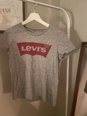 Levi's t-shirt - Snygg grå t-shirt från Levi's med klassisk röd logga framtill. T-shirten har rund halsringning och korta ärmar, perfekt för en avslappnad och trendig stil. Tillverkad i mjuk bomull för skön komfort hela dagen.
