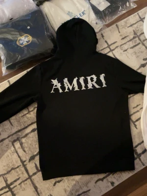Amiri Hoodie - Säljer en helt ny Amiri hoodie som är i storlek M, berätta hur lång du är och hur mycket du väger så att jag svarar om den passar eller inte.. Passar perfekt inför vintern, håller dig stilig och varm. Om du vill köpa den vita så finns den i min profil. Passa på och köp❄️