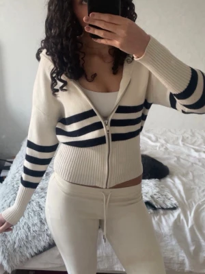Vit zip hoodie med svarta ränder - Säljer en ribbstickad vit hoodie med dragkedja och svarta ränder från Zara. Jättemysig och i jättebra skick! Passar S-M🩷