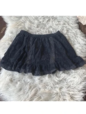 Svart lågmidjad Abercrombie & Fitch spetskjol med volang - Supersöt svart lågmidjad kortkjol i spets med volangkant. Kjolen har elastisk midja och fina spetsdetaljer som ger en romantisk vibe. Perfekt att styla med en enkel topp eller stickad tröja. Passar dig som gillar feminina och trendiga plagg. Supersnygg. Använd gärna köp nu❤️