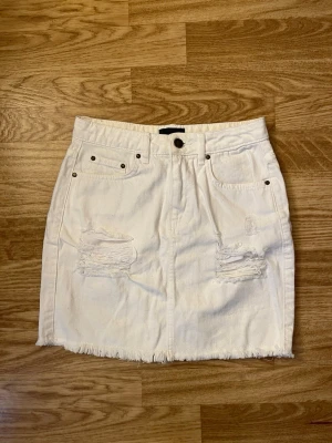 Vit jeanskjol från NLY Jeans XS - Säljer en vit jeanskjol från NLY Jeans i storlek XS. Kjolen har slitna detaljer framtill. Den är aldrig använd då den är för liten för mig. 