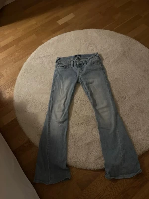 True Religion Joey Low Rise Flare Jeans - Säljer ett par ljusblå True Religion Joey jeans i storlek W26. Har dock sytt upp de men passar på en som är 165. Säljer pga har växt ur längden och är för stora i midjan. Köpt på jeans bolaget innan.
