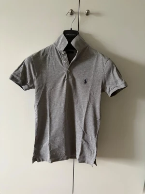 Grå Polo Ralph Lauren piké - Grå Polo RL piké i storleken XS slim fit. Mycket bra skick, kommer strykas innan leverans! Säljes då den är för liten.