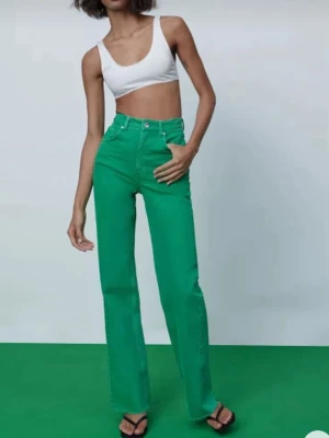 Gröna raka jeans med hög midja - Snygga gröna jeans med rak passform och hög midja. Jeansen har klassisk femficksdesign och stängs med knapp och dragkedja. Perfekta för dig som vill sticka ut med färg och ändå ha en clean look.