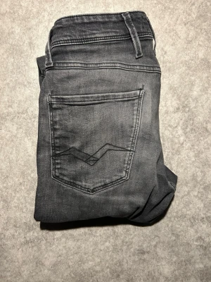 Mörkgrå Replay jeans, slim fit - Snygga mörkgrå jeans från Replay med klassisk femficksdesign och diskreta slitningar. Jeansen har smal passform och raka ben, tillverkade i mjukt denimtyg som sitter skönt hela dagen. Perfekta för en stilren och avslappnad look. W28L30