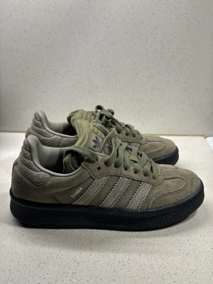Adidas Samba sneakers i olivgrön mocka - Adidas Samba sneakers i olivgrön mocka med svart sula. Skorna har snörning och en retro look med rund tå och låg profil. Har använt 2-3 gånger, Därav priset, brukar ha 37 och dom passar jättebra.