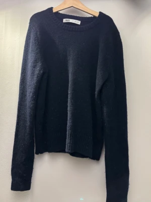 Mörkblå stickad tröja från Zara - En enkel och stilren mörkblå stickad tröja från Zara. Tröjan har rund halsringning, långa ärmar och ribbade muddar vid ärmslut och nederkant. Mycket enkel att styla och passar till nästan allt! 