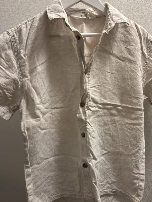 Vit linneskjorta från H&M barn 134 - Säljer en stilren vit skjorta från H&M i linne och bomull.