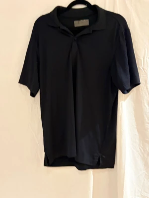 Svart Callaway piké  - Säljer en svart pikétröja från Callaway med klassisk krage och knappslå. På ärmen finns en snygg vit Callaway-logga broderad. Tröjan är tillverkad i ett mjukt och lätt material som passar perfekt för golf eller andra sportiga aktiviteter.