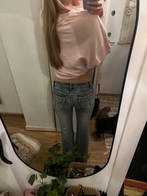 Blå bootcut jeans med rhinestones❤️ - Säljer ett par snygga blå bootcut jeans från Bonny girl med låg midja. Jeansen har coola paljettdetaljer och broderier på fickorna både fram och bak. Materialet är klassisk jeans med lite stretch! Mått: Midja rakt över= 35 cm innerbenslängd=84cm Jensen är som sagt stretchiga så midjan passar som lite större