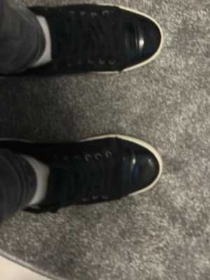 Svarta sneakers från Lanvin - Svarta sneakers från Lanvin med rund tå och platt vit sula. Skorna har snörning med svarta skosnören och metallöglor. Ovandelen är i svart skinn med en blankare finish på tån. Klassisk och stilren design med diskret logga på sulan.pris går att diskutera.