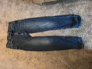 Dressman  blå jeans straight fit - Klassiska blå dressman jeans med rak passform. Jeansen har en snygg tvätt med lätt slitning på låren och kontrastsömmar. Tillverkade i robust denim av bomull, perfekta för en avslappnad och tidlös stil.