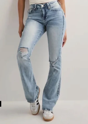 True Religion Becca Bootcut Jeans 27 - (Orginal priset är 1299❤️)                                 Säljer ett par ljusblå True Religion Becca Mid Rise Bootcut jeans i storlek 27. De har ikoniska bakfickor med röd kontrastsöm, slitningar framtill och på knäna och silverfärgade knappar. Klassisk bootcut-modell med snygg tvätt och detaljer som sticker ut.❤️ Aldrig varit andvönder bara testat när jag fick dom💕Det är därför dom säljs🥰 köpta på Nelly❤️