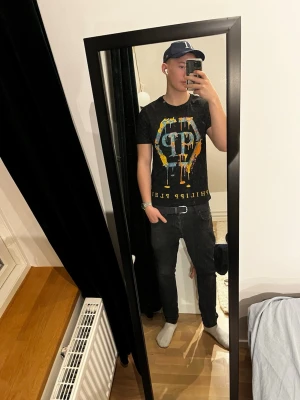 Philipp Plein T-shirt  - Säljer en svart t-shirt från Philipp Plein med stort färgglatt tryck och logga på bröstet. T-shirten har korta ärmar och rund hals. Materialet är mjuk bomull och passformen är normal. Perfekt för dig som gillar streetwear och snygga prints.