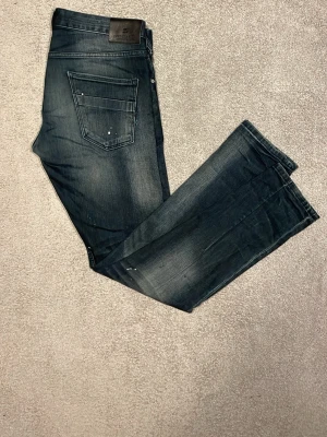 mörkblåa jeans från Scotch & Soda - Snygga mörkblåa jeans från Scotch & Soda med coola slitningar och diskreta färgstänk. Modellen passar slimfit och är iprincip i nyskick, men passade inte mig. 