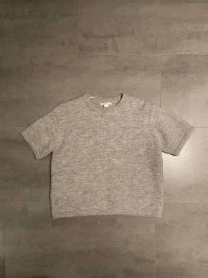 stickad kortärmad tröja från Gina tricot  - Stickad tröja i grå från Gina tricot i storlek 158/164/XS, helt oanvänd