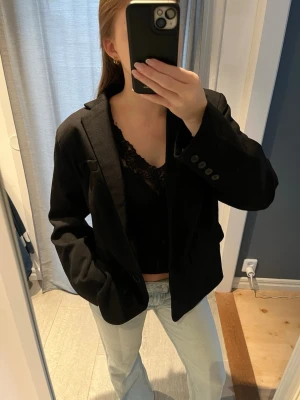 Svart kavaj  - Svart kavaj med klassisk krage och tre knappar framtill. Snyggt skräddad med långärmade ärmar och lätt oversized look