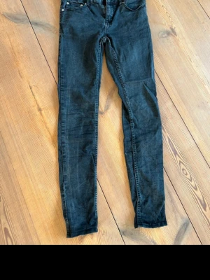 Svarta skinny jeans från 157, S - Svarta skinny jeans från 157 i storlek S. Modellen är smal och sitter tight längs benen, med klassisk femficksdesign och dragkedja fram. Jeansen har en mörk tvätt och är tillverkade i stretchigt bomullsmaterial för skön passform.