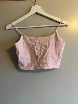 Ljusrosa linnetopp från Garage - Säljer en ljusrosa linnetopp från Garage i storlek M. Toppen har smala axelband och är croppad med en enkel, stilren design. Perfekt för varma dagar och att styla med dina favoritjeans eller kjol. Materialet känns mjukt och lätt mot huden.