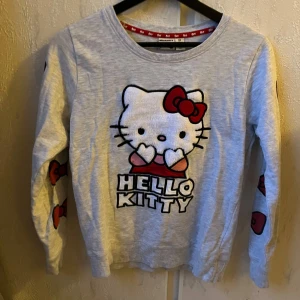 Hello kitty tröja - Supersöt hello kitty tröja med rosetter på ärmarna. Storlek XS med tight passform.