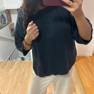 Mörkblå stickad tröja med loose fit - Säljer en mörkblå stickad tröja med loose passform och trekvartsärmar. Tröjan är mjuk och har en enkel. Stl M från lager 157