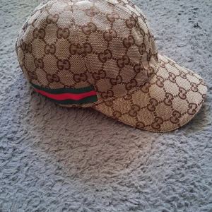 beige keps med logomönster - Kepsen är helt ny och aldrig använt 