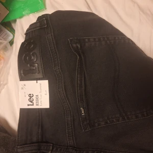 Svarta bootcut jeans Lee Jessica - Säljer ett par svarta Lee Jessica jeans med bootcut-modell och låg midja. Jeansen är i klassisk denim med fem fickor, Lee-logga på bakfickan och snygga detaljer. Perfekta för dig som gillar en tidlös och cool look.