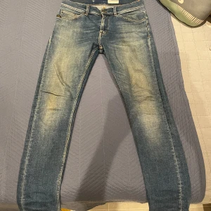 Tiger of Sweden Evolve jeans blå 30/30 - Snygga blå jeans från Tiger of Sweden, modell Evolve. De har en slim passform med klassisk femficksdesign och coola slitningar framtill och baktill. Jeansen har orangea sömmar och ett brunt läderpatch med logga bak i midjan. Perfekt för dig som gillar stilrena och moderna jeans.