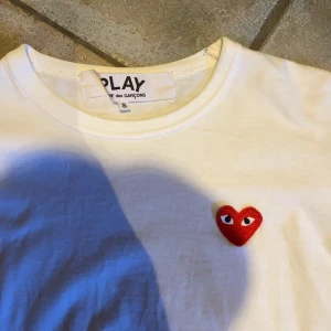 Vit långärmad tröja Comme des Garçons - Säljer en vit långärmad tröja från Comme des Garçons Play med det ikoniska röda hjärtat broderat på bröstet. Tröjan är i mjuk bomull och har en klassisk passform med rund hals. Perfekt för dig som gillar stilrena och trendiga plagg.