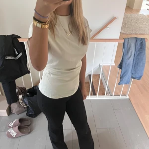 Vit blus med korta ärmar - Säljer en stilren vit blus med korta ärmar och hög hals. Blusen har en lätt figurnära passform och är tillverkad i ett mjukt, slätt material som ger en elegant look. köpt på plick💗