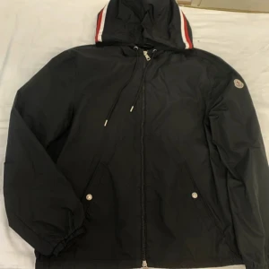 Svart vindjacka från Moncler  - Svart vindjacka från Moncler med huva och dragskedja. Storlek M passar som storleken. Använd fåtal gånger i perfekt skick. Skriv vi eventuella frågor. Pris kan diskuteras.