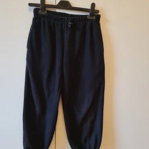 Svarta fleecebyxor från B.fly Wear 5-6 år 110/116 cm - Mysiga svarta fleecebyxor från B.fly Wear med resår i midjan och benslut. Passar för barn 5-6 år.