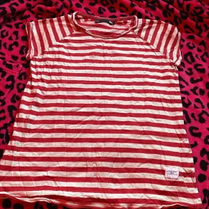 Randig röd och vit t-shirt från 157 - Säljer en chill t-shirt från 157 State Craft i storlek XS. Den har röda och vita ränder, rund hals och korta ärmar. Mjuk och skön, perfekt för dig som gillar klassisk streetstil. Märke och etikett syns tydligt på framsidan.