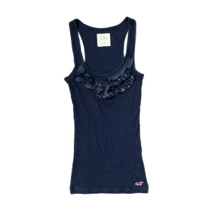 Hollister linne - Jättegulligt marinblått linne från gamla hollister med spets, volanger och paljetter. Färgen visas bäst på första bilden. Storlek xs och fint skick. Använd köp nu!!