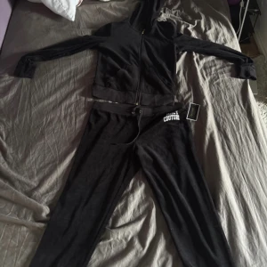 Svarta mjukisbyxor Juicy Couture M - Svarta mjukisbyxor från Juicy Couture i storlek M. Byxorna har snörning i midjan och vit broderad logga på höften. Mjukt material med skön känsla, perfekt för chill dagar. Klassisk Juicy Couture-stil med matchande hoodie finns.Unik stil köpt i USA
