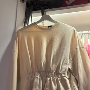 Beige långärmad tröja med rynk - Säljer en beige långärmad tröja med rund hals och snygg rynkdetalj i midjan . Tröjan är gjord i mjuk bomull och passar perfekt för dig som gillar enkel men trendig stil. Köpt secondhand, men aldrig använt! ⭐️ hör av er om fler bilder eller funderingar!