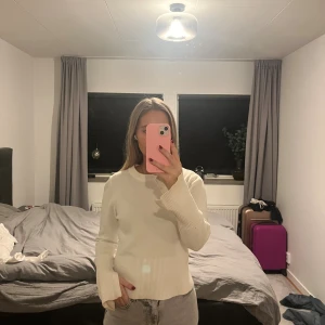 Vit stickad tröja med slits i ärm - Säljer en vit stickad tröja med rund hals och långa ärmar. Tröjan har ribbade muddar och en snygg slitsdetalj vid ärmsluten samt i sidorna. Perfekt för dig som gillar en enkel men trendig look.