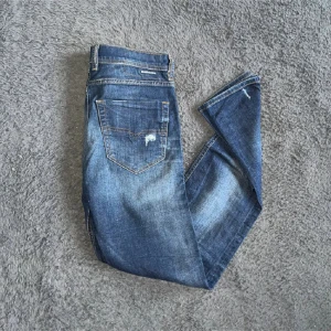 Diesel jeans  - Snygga blå Diesel Tepphar Med slitna detaljer på både fram- och baksida. Jeansen har klassiska fem fickor, orange sömmar och är tillverkade i stretchigt denim för extra komfort. Perfekt för dig som gillar en smal siluett och coola slitningar. Midja 39cm längd 109cm. Ifall det inte finns någon bild i annonsen där jag bär plaggen jag säljer så är det för att jag ej kan ha storleken heller passformen, så kolla måtten för storlek och googla på modellnamnet för passform 😉(S)
