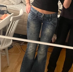 Lågmidjade bootcut jeans  - Jag säljer ett par jättesnygga lågmidjade bootcut jeans som tyvärr är för små för mig. Märket är house jeans. Dom är lite slitna längst nere vid benen men har inga andra defekter. Det står w27 i dom vilket jag tror är storleken men annars står måtten här. Tvättas innan dom skickas. Midjemått(rakt över)- 40 cm och innerbens längd 82 cm.                                                              