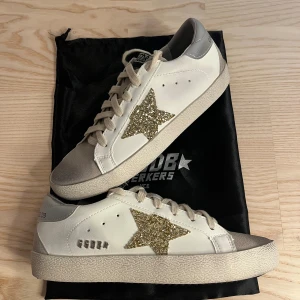 Golden Goose sneakers med glitterstjärna - Snygga vita Golden Goose sneakers med beige snörning, grå mockadetaljer på tå och silverfärgad häl. 😊