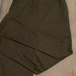 Svarta kostymbyxor med hög midja - Snygga svarta kostymbyxor med hög midja och raka ben. Byxorna har en stilren look och är tillverkade i ett mjukt tyg som känns bekvämt hela dagen. Perfekta för dig som gillar en clean och klassisk stil.